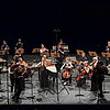 Musikensemble mit Instrumenten auf einer Bühne mit schwarzem Hintergrund