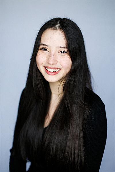 Alina Ju Tchin Simon in front of a light blue background