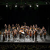 Musikensemble mit Instrumenten auf einer Bühne mit schwarzem Hintergrund