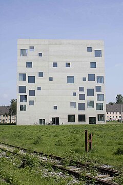 SANAA-Gebäude. Im Vordergrund Rasen und alte Gleise.